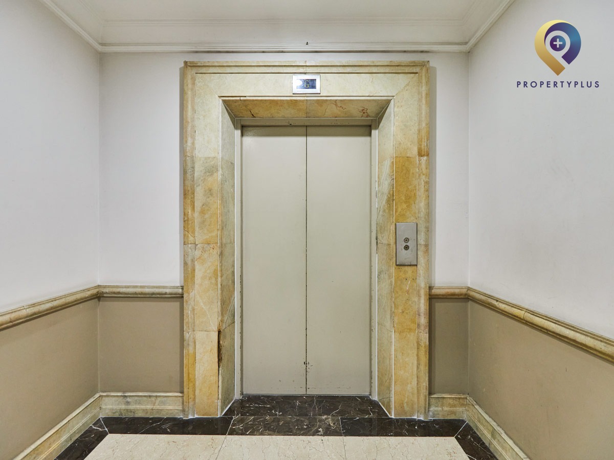 Elevator door inside The Manor office building with marble wall and clean design.